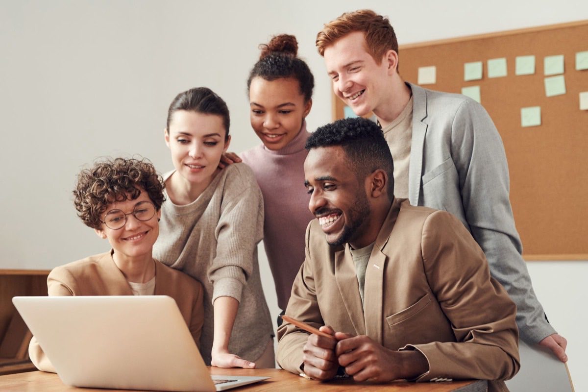 Colleagues gathered around a laptop, working through a problem together