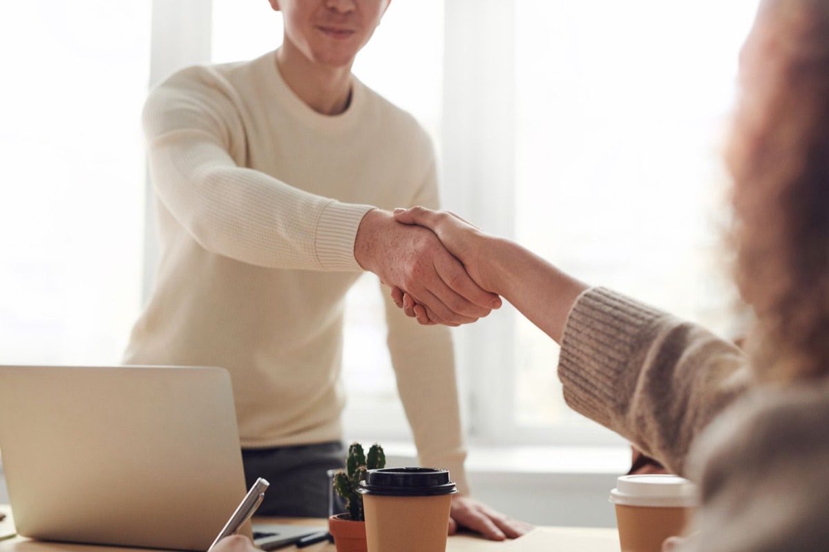 Two people shaking hands across a table after reaching an agreement